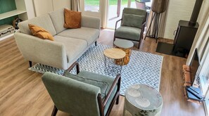 Woonkamer met 2 zitsbank, 2 fauteuils en een houtkachel.