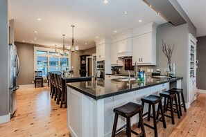 Spacious and modern kitchen with a large island, stainless steel appliances, and elegant lighting, seamlessly flowing into a bright, open living area—perfect for entertaining.