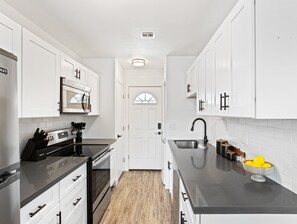Fully equipped kitchen stocked with basic cooking essentials, stainless steel appliances, access to the shared backyard, and a washer and dryer.