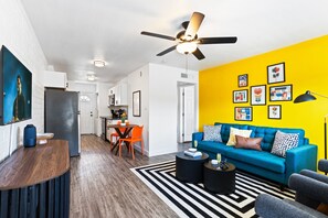 Bright and stylish living room featuring a vibrant yellow accent wall, cozy seating, and modern decor—perfect for relaxing or enjoying a movie on the Smart TV.
