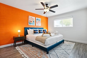 Inviting bedroom with a king-size bed, vibrant accent wall, and designated closet space—designed for ultimate comfort and relaxation after a day of exploring.