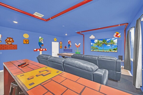 A vibrant gaming room with bean bags, sofas, ergonomic chairs, multiple screens, and consoles.