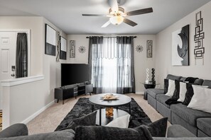 Relax in style in our chic living room with sleek black and gray decor. Enjoy the plush comfort of the couch and loveseat while streaming your favorites on the large flat-screen Roku TV. Complete with a ceiling fan for a breezy feel!