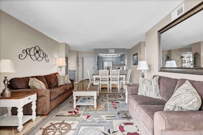 A charming living room with plush seating, perfect for gathering with friends and family. Large windows let in plenty of light, adding to the warm, welcoming vibe.