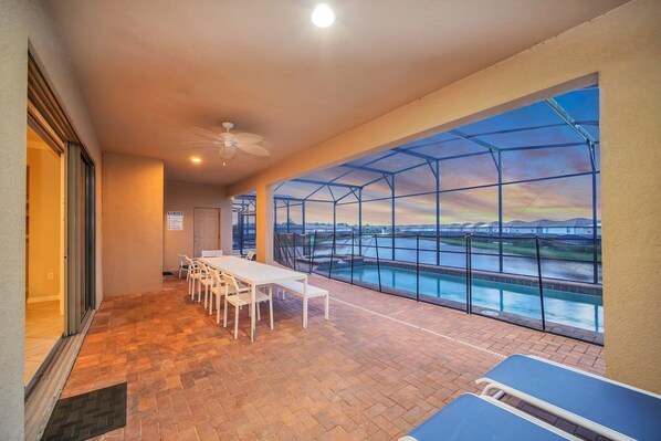 Screened pool with brick patio, blue seats, and scenic water views for relaxation.