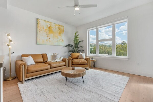 Beautifully designed living room. 65" TV, leather sofa and amazing views of mountains and city skyline.