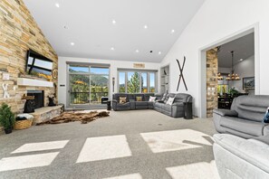 Spacious living area featuring a flat screen TV above a wood burning fireplace, ample seating, and access to one of two private balconies.