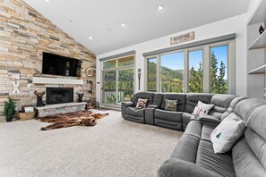 Spacious living area featuring a flat screen TV above a wood burning fireplace, ample seating, and access to one of two private balconies.