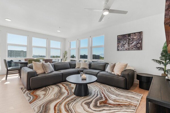 Beautifully designed living room. 75" TV, leather sofa and amazing views of mountains and city skyline.