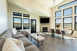 Living room with large sectional sofa, 65" Roku Smart TV, gas fireplace, and balcony access