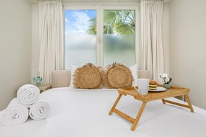 This beautifully bright bedroom welcomes you with a cozy king-sized bed dressed in fresh, clean linens and plush, soft pillows.