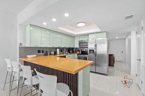 A convenient breakfast bar with four cushioned bar stools for a quick snack, coffee, or to work on your laptop if needed
