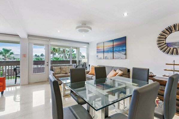The dining area features a glass table that comfortably seats