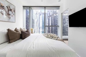 The master bedroom with a queen sized bed, plush pillows and a 40 inch smart TV.