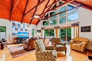 Spacious and inviting living room with vaulted wooden ceilings, large windows, and comfortable seating, perfect for relaxing in style