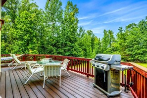 Spacious outdoor deck with a grill, dining table, and lounge chairs, perfect for enjoying a BBQ and the surrounding nature