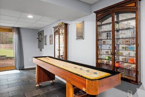 Basement level game room with shuffleboard, lots of outdoor games, board games, darts, and seating options to enjoy company with friends and family. 