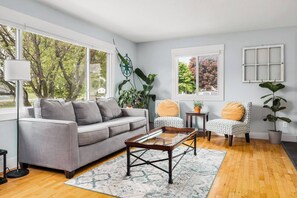 Main floor living area with smart tv, seating, cellular shades, live plants, and lots of sunlight. 