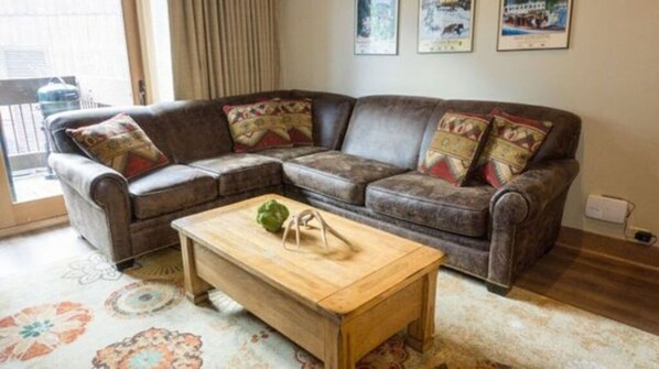 Unwind in this inviting living room, featuring plush leather seating, vibrant decor, and ample natural light.