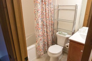 Bright and functional bathroom with a full shower, clean design, and floral accents for a refreshing touch.