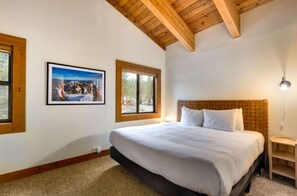Spacious bedroom with a charming vaulted wooden ceiling, a comfortable bed, and serene decor for a restful night's sleep.