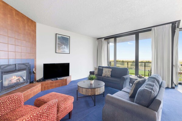 Cozy living room with a fireplace, ample seating, and large windows that let in plenty of natural light. Perfect for relaxing and enjoying time together.