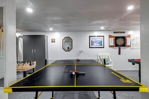 Exciting game room with a pool table, ping pong, darts, foosball, basketball game, Roku TV, and a small bar area—everything you need for a great time.