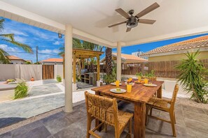 Relax and enjoy alfresco dining by the pool in this outdoor oasis. The space features a set of comfortable tables and chairs, perfect for gathering with family or friends.