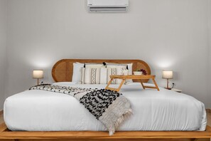 Step into this airy and inviting bedroom, where relaxation meets style. The plush bed is dressed in soft linens, offering a perfect retreat for restful nights
