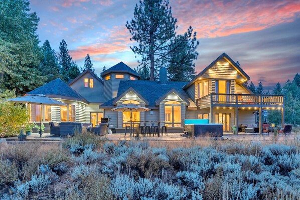 Exterior: View of the back of the home, spacious outdoor patio, outdoor dining table, 6-person hot tub, Martis Valley views, secluded setting