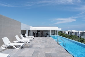 Rooftop lounge area with sunbeds and scenic views.