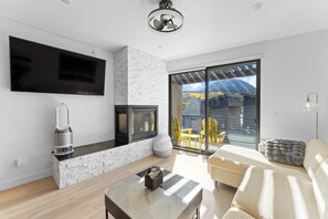Open concept living area featuring a gas fireplace, flat screen TV, queen sleeper sofa, remote control blinds, and air purifier.