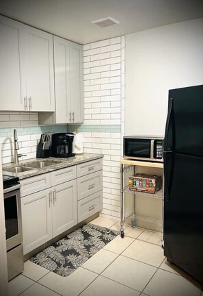 Fully stocked kitchen with pots, pans, dishware, silverware, coffee maker, toaster, blender, knives, drinking glasses, and microwave. 