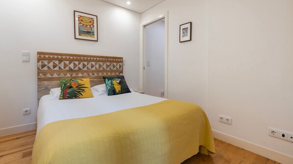 A cheerful bedroom with colorful pillows, wooden textures, and a warm yellow blanket for a relaxing stay. #RestfulRetreat #TropicalVibes