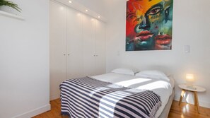 A striking feature wall with vibrant artwork adds character to this bright, minimalist bedroom. #BedroomGoals #CreativeDesign