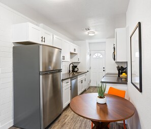 Unit 1: Sleek and functional kitchen equipped with stainless steel appliances, modern cabinetry, and a cozy dining nook—perfect for enjoying a quick meal or morning coffee.