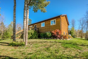 A charming log cabin-style exterior surrounded by nature, with large windows and a welcoming front deck.