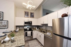 Modern kitchen with sleek granite countertops, stainless steel appliances, and stylish pendant lighting. The open layout offers a bright, contemporary feel, perfect for preparing meals and entertaining.