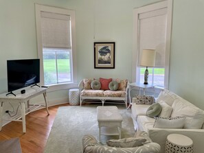 Tower living room with 55" Smart TV, windows overlooking grounds, oak floor.