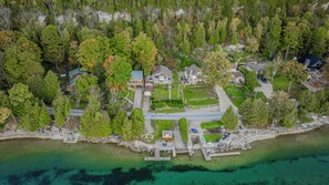 An aerial perspective of the peaceful neighborhood, showcasing the cottage’s proximity to the water and its lush surroundings.