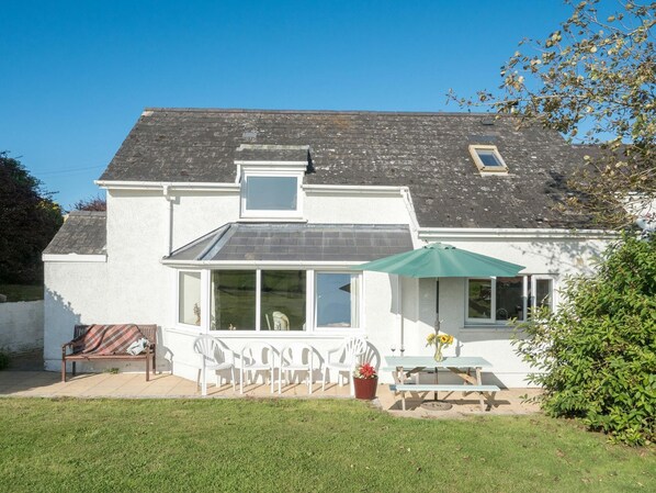 y bwythn garden with lawn and patio with picnic table, green parasol, chairs and bench