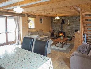 Open plan living / dining area with table, dining chairs, sofas, logburner and open tread stairs