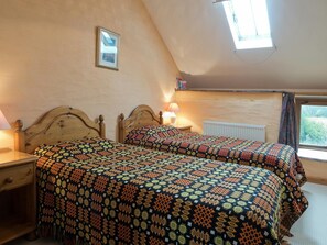 Twin bedroom in Y Cartws with beds, bedside cabinets, lamps, a radiator and 2 windows.