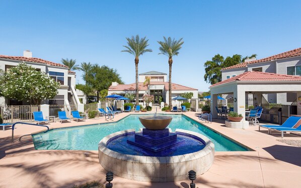 Enjoy the community pool area featuring a refreshing pool, relaxing spa, gas grills, outdoor dining tables with umbrellas, and plenty of sun loungers for the ultimate day of leisure.