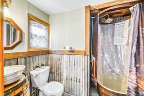 Rustic bathroom featuring a unique barrel sink, corrugated metal accents, and a cozy walk-in shower.