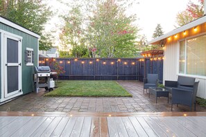 Lighted deck, paver surrounding lawn & string lights for warm illumination.