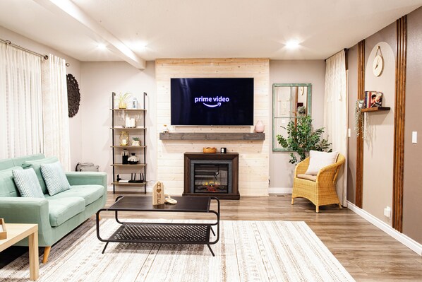 Open living room with sofa, love seat, fireplace and 65in smart TV