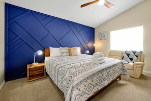 Unwind in this spacious master bedroom, complete with a striking blue accent wall, cozy lighting, and a plush king-sized bed. A perfect retreat after a day of exploring.