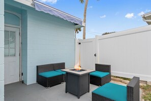 The backyard features a cozy firepit surrounded by ocean-colored accents, perfect for relaxing under the stars