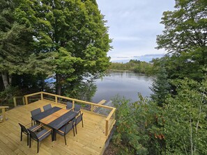 A stunning lakeside deck with a modern dining set, perfect for meals with a view! Surrounded by lush trees, it’s the ideal spot for a serene getaway. 